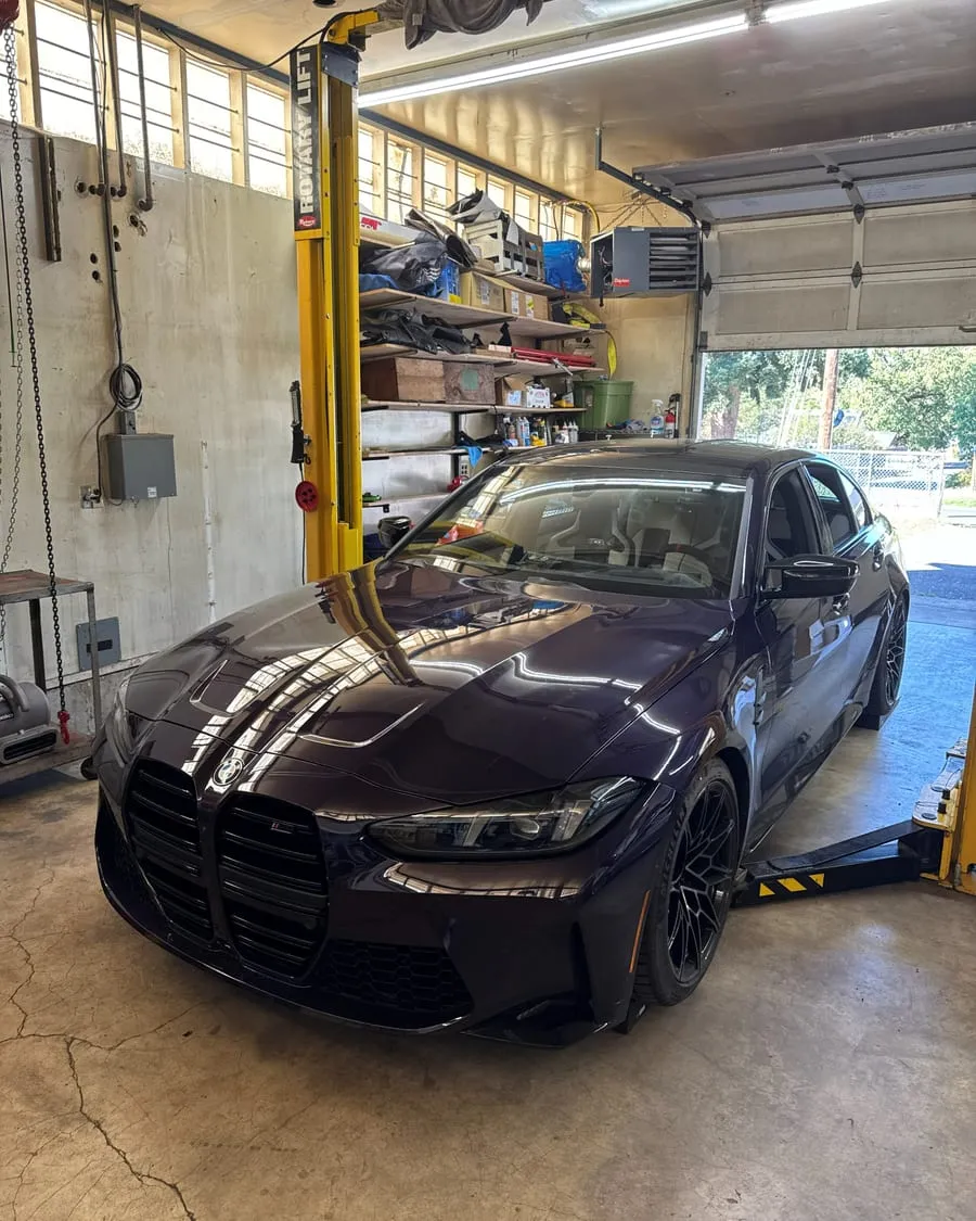 BMW G80 M3 Competition on the lift for a performance exhaust install at PDXEuroWerks, a Portland BMW specialty shop in Oregon